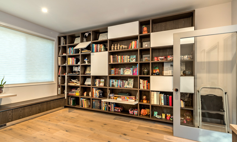 The expansive library and home office features a wall of shelves with cabinet doors interspersed throughout.