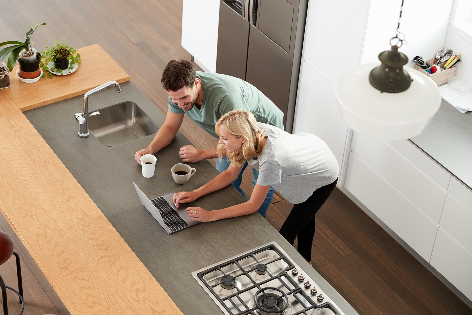 Man and woman looking at laptop in modern kitchen