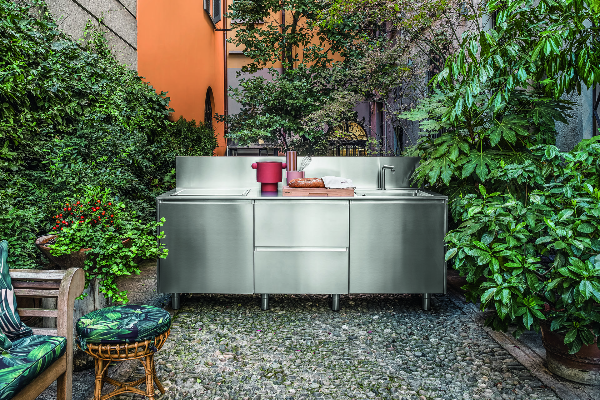 Stainless steel outdoor kitchen in lush green garden