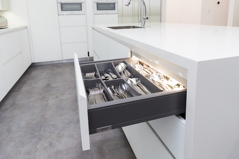 Organized European kitchen drawer with internal dividers for utensils and accessories.