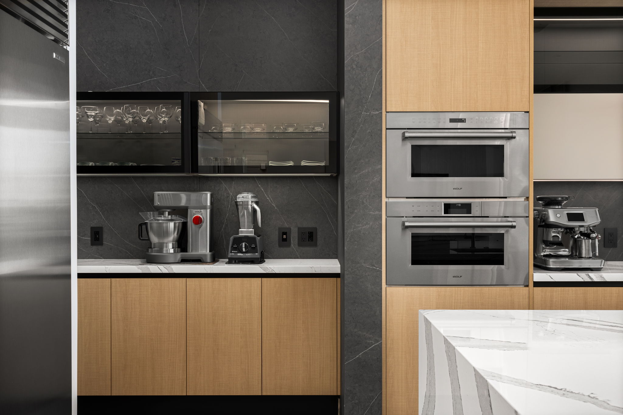 European kitchen with strategic use of wood cabinetry, integrated appliances, and refined stone surfaces in a Foster City home remodel.