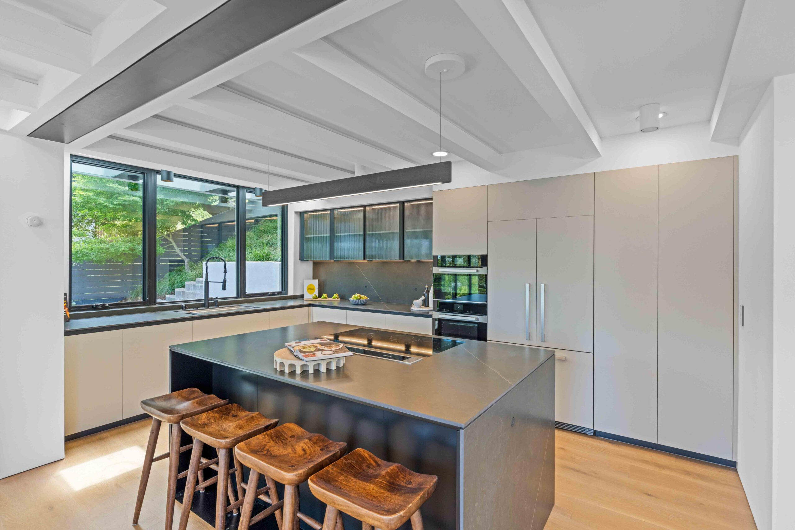 Modern kitchen designed around natural light, featuring expansive windows, integrated cabinetry, and a central island in a Bay Area home.