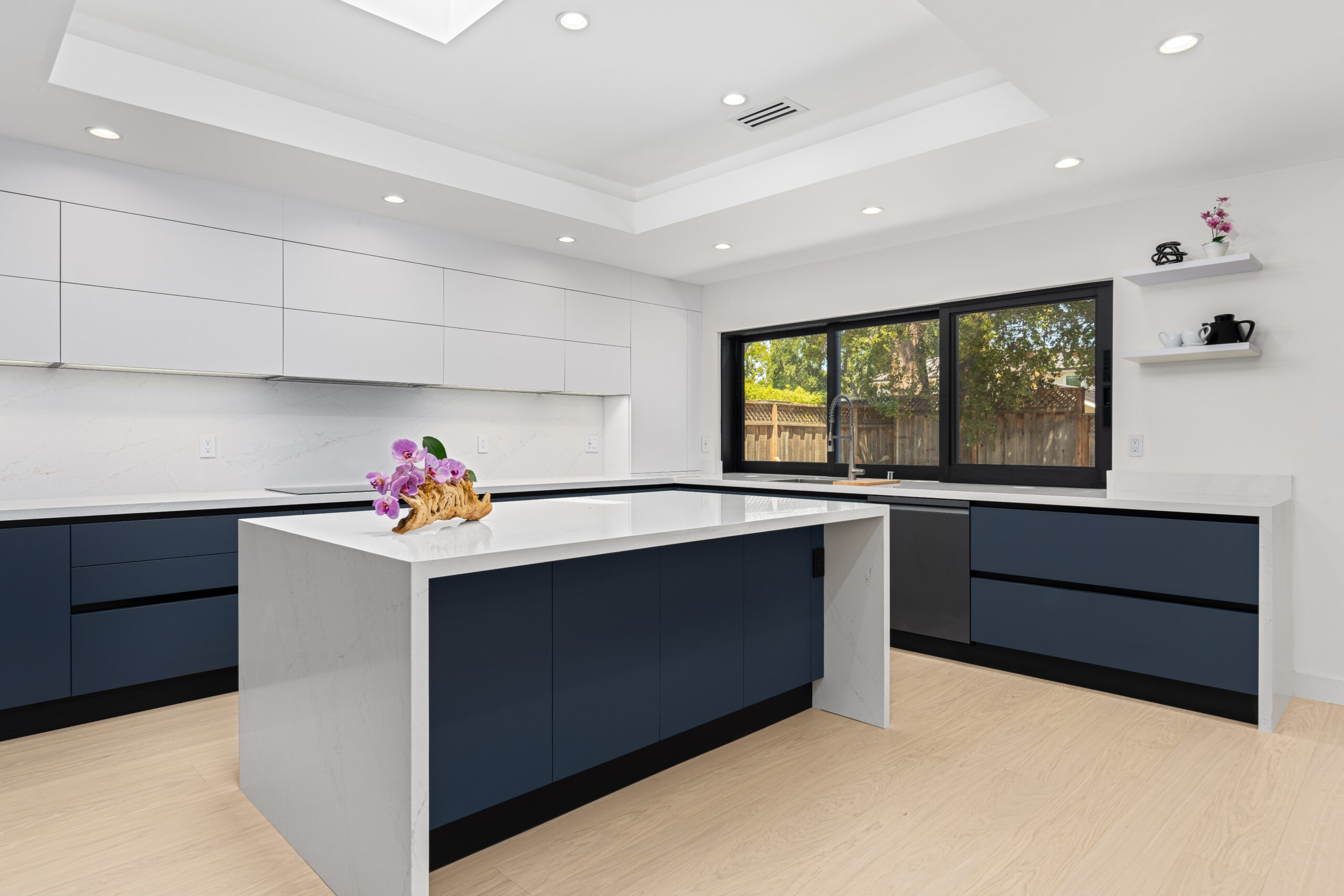 Modern blue kitchen with concealed appliances and integrated cabinetry, featuring a waterfall island and refined marble surfaces in a Mountain View home.