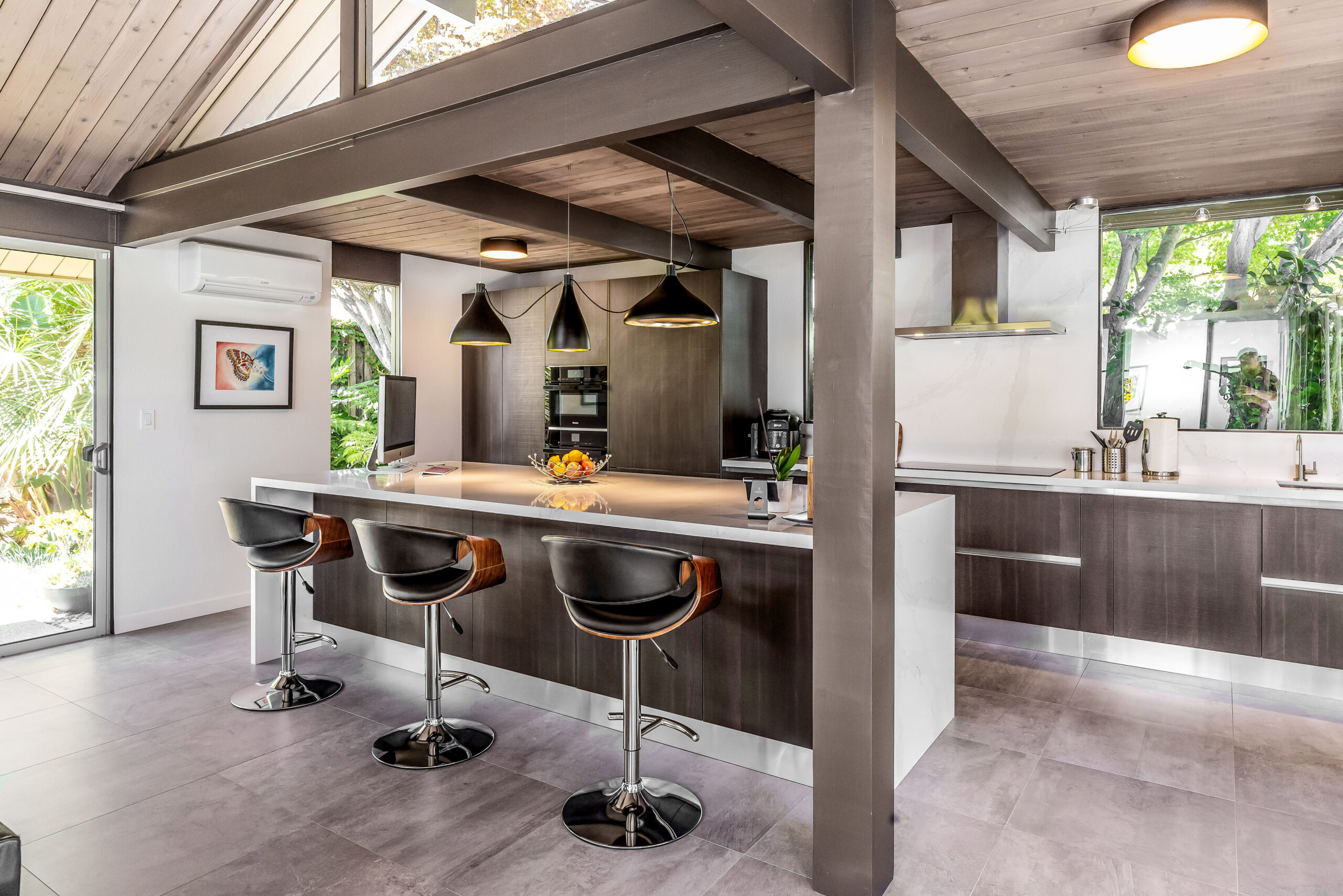 Architecture-led modern kitchen in a Sunnyvale Eichler home, featuring exposed beams, warm wood cabinetry, and an indoor-outdoor layout.